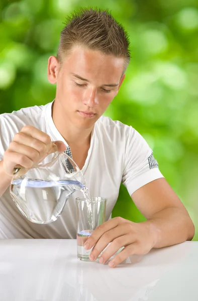 Мальчик наполняет воду в стакане — стоковое фото