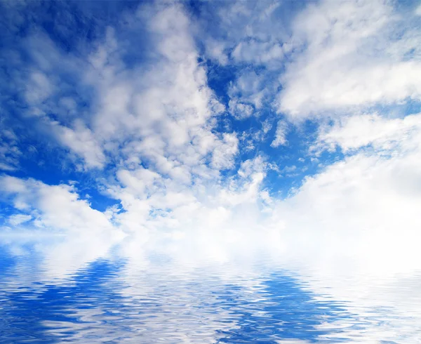 Weiße, flauschige Wolken mit Regenbogen am blauen Himmel — Stockfoto