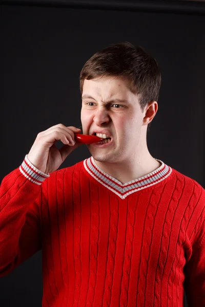 Young guy eats pepper. A series of consecutive shots. — Stock Photo, Image