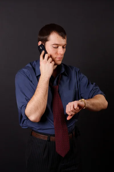 Бизнесмен по телефону смотрит на часы — стоковое фото