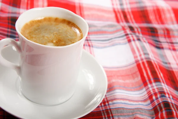 Šálek kávy na červený ubrus — Stock fotografie