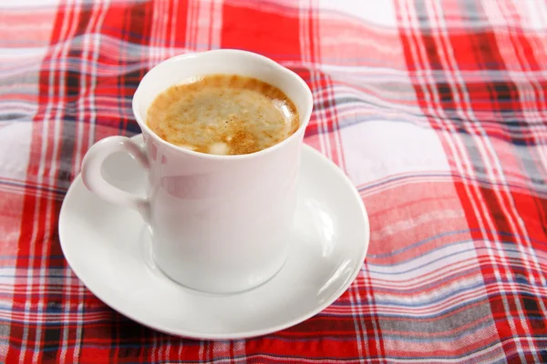 Tasse Kaffee auf roter Tischdecke — Stockfoto