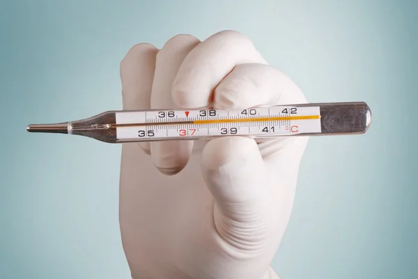 Hand och en termometer på en grå bakgrund — Stockfoto