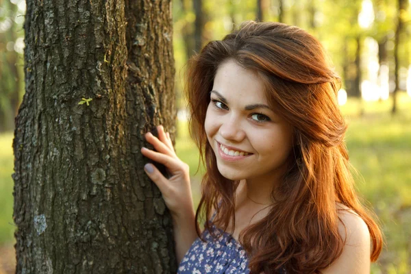 Retrato de mulher jovem abraçando uma grande árvore em um parque — Fotografia de Stock