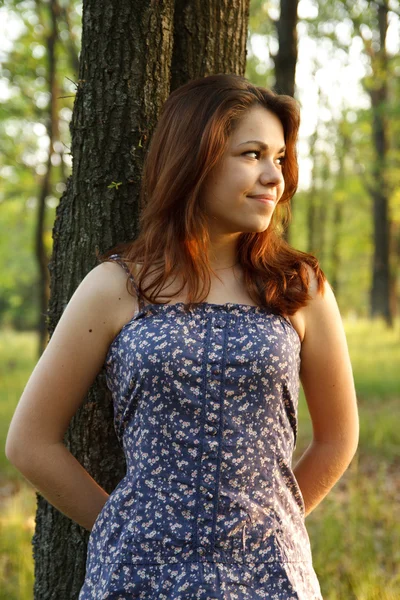 Portret van een jonge vrouw een grote boom knuffelen in een park — Stockfoto
