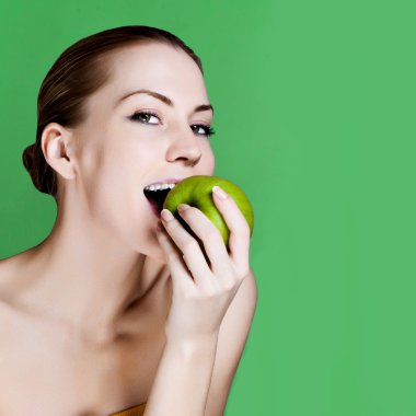 Woman eating apple smiling on green background. Healthy eating candid woman. clipart