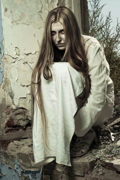 Zombie-Mädchen sitzt in verlassenem Gebäude — Stockfoto
