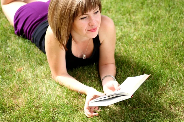Hermosa joven mujer leyendo el libro al aire libre — Foto de Stock
