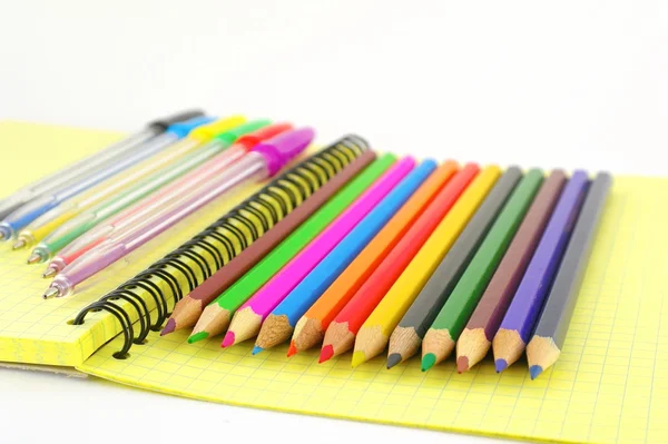 Stylo et crayons de couleur sur le livre d'écriture jaune — Photo