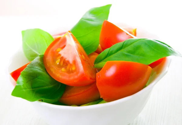 Frische Tomaten mit Basilikumblättern in einer Schüssel — Stockfoto