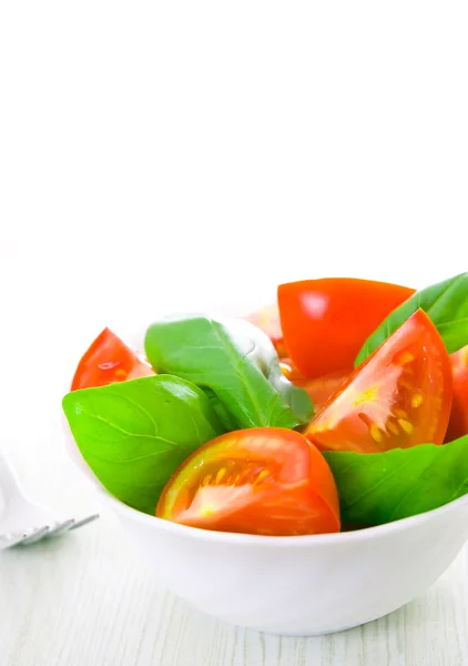 Fresh tomatoes with basil leaves in a bowl — Stock Photo, Image