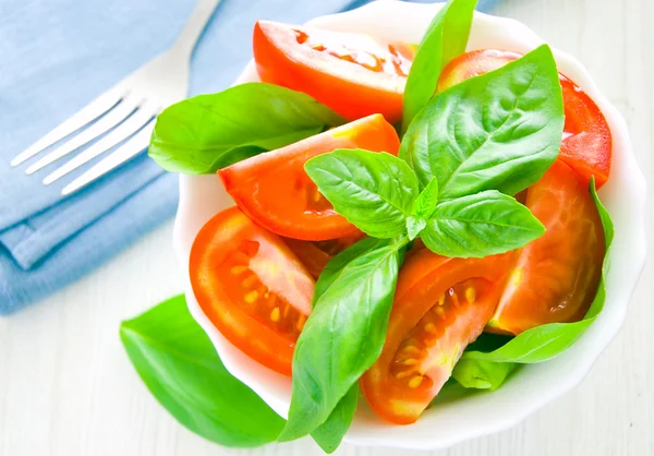 Świeże pomidory z bazylią pozostawia w misce — Zdjęcie stockowe