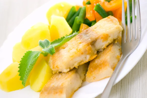 Жареная рыба с овощами и картошкой на ужин — стоковое фото