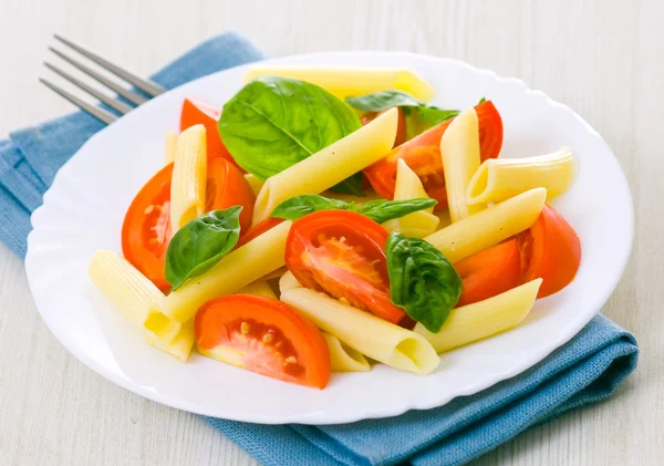 Салат из пасты с помидорами и свежими листьями базилика — стоковое фото