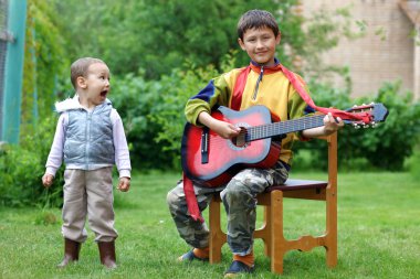 Two funny boys music student singing and playing the guitar outd clipart