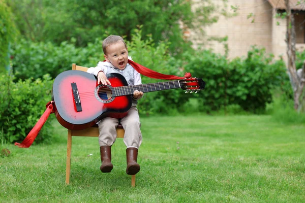 Маленький студент, поющий и играющий на гитаре — стоковое фото