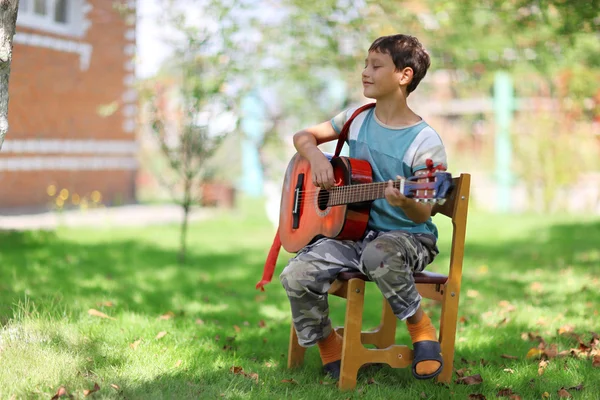 Estudiante de música tocando la guitarra al aire libre Imagen de archivo