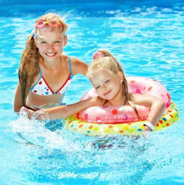 Children sitting on inflatable ring on water. clipart