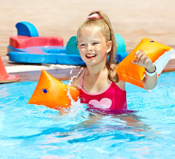 Criança com braçadeiras brincando na piscina . — Fotografia de Stock