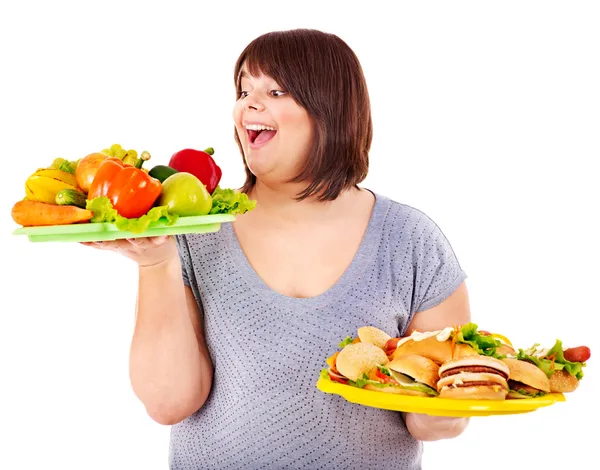 Kadın meyve ve hamburger arasında seçim yapma. — Stok fotoğraf