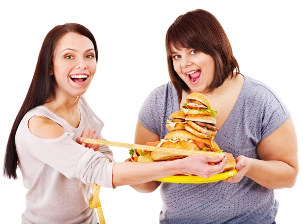 Mulher segurando fast food e fita métrica . — Fotografia de Stock