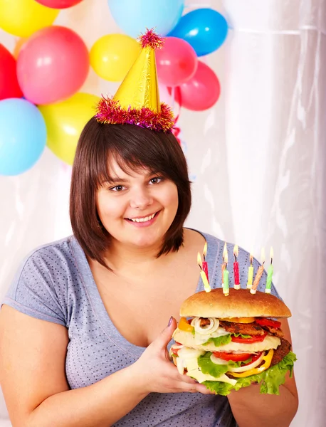 Woman eating hamburger at birthday. Stock Picture