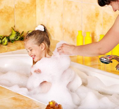 Mother and child washing in bubble bath . clipart