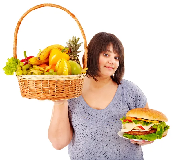 Γυναίκα επιλέγοντας μεταξύ φρούτα και χάμπουργκερ. — Φωτογραφία Αρχείου