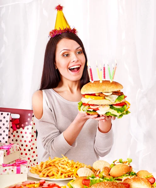 Жінка їсть гамбургер на день народження . — стокове фото