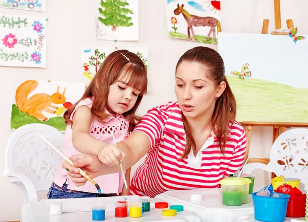 Παιδί με χρώματα κλήρωση δάσκαλος στην αίθουσα παιχνιδιών. — Φωτογραφία Αρχείου