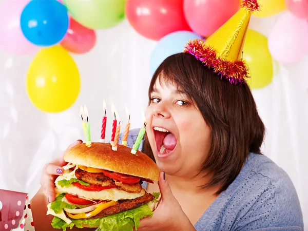 Woman eating hamburger at birthday. Stock Photo