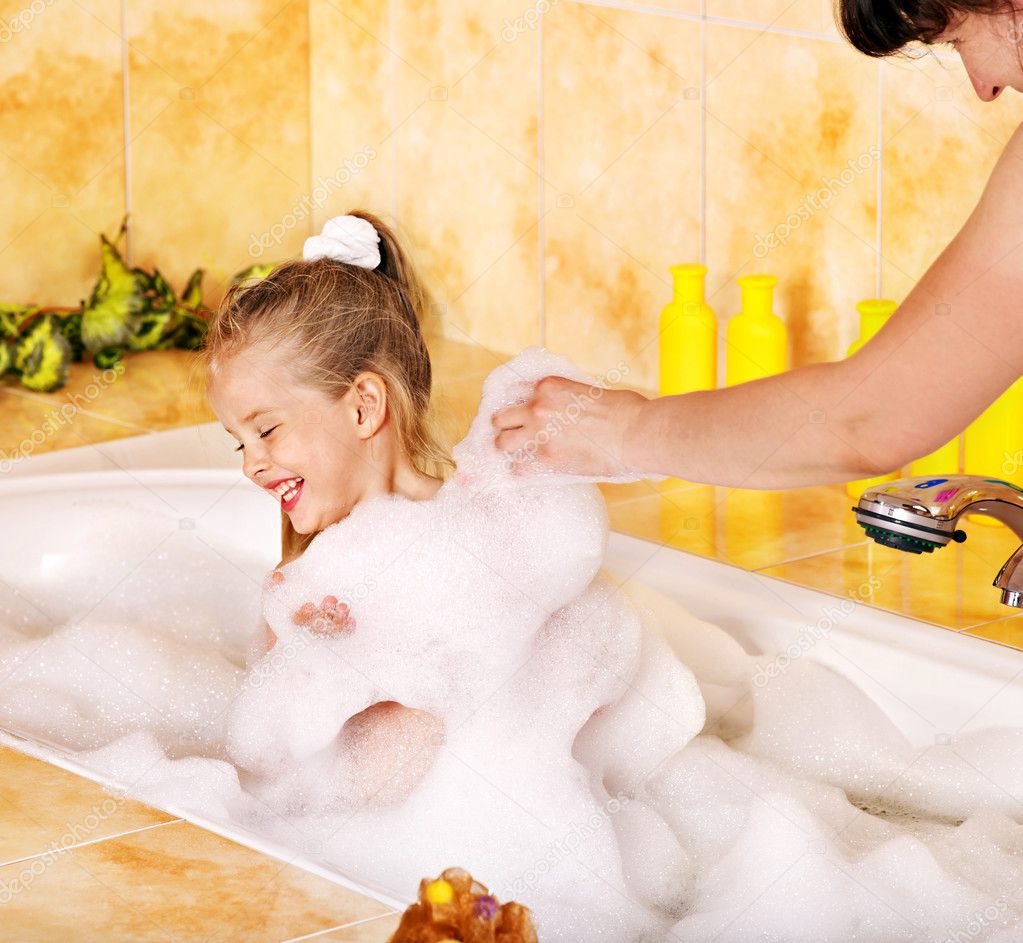 Mother and child washing in bubble bath .