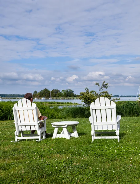 stock image Single senior man in white chairs overlooking bay