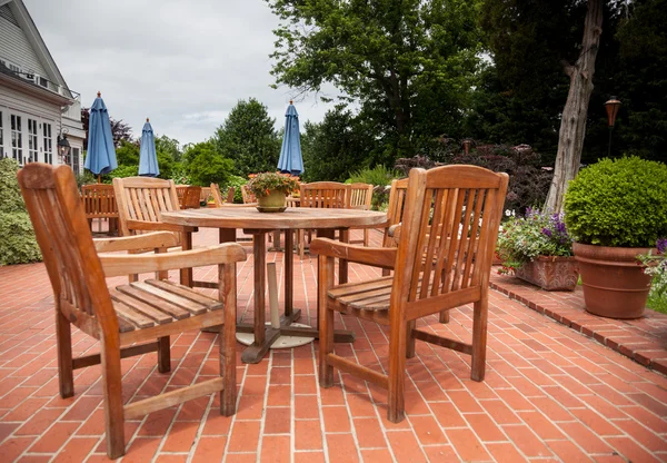 Teak patio tables and chairs on brick deck — Stock Photo, Image