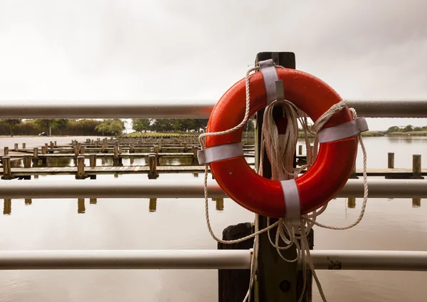 Cinturão de vida vermelho na frente do porto de doca de barco vazio — Fotografia de Stock