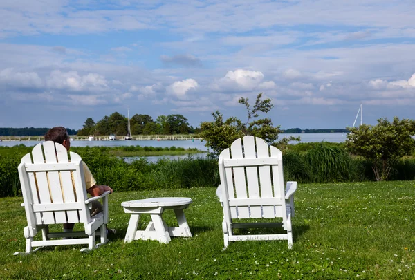 Single senior man in white chairs overlooking bay — Stock Photo, Image