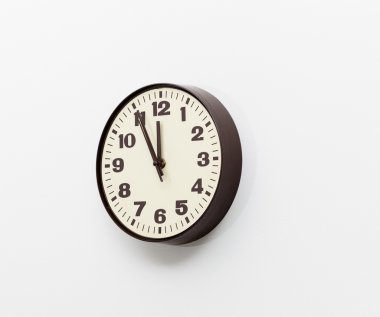 Brown clock on white office wall near noon clipart