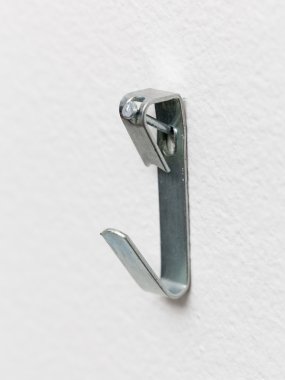 Macro of steel picture hook nailed to wall clipart