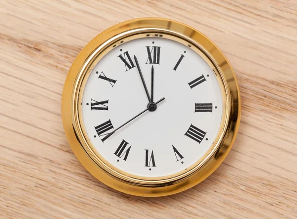 Латунные маленькие часы или часы на деревянном столе — стоковое фото