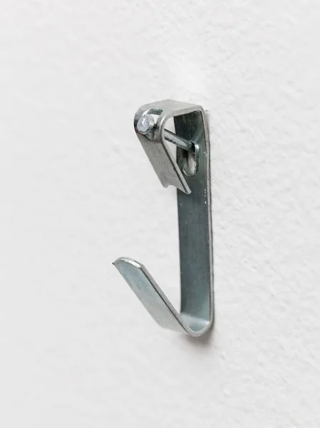Macro of steel picture hook nailed to wall — Stock Photo, Image