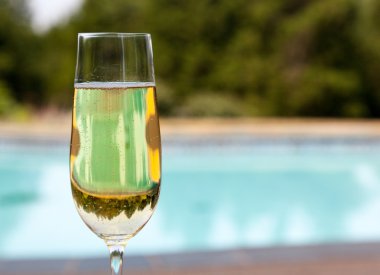 Flute of cold champagne by side of pool clipart