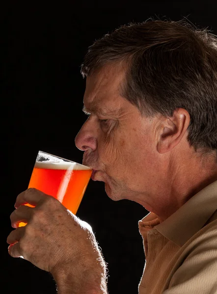 Homem sênior sorvendo de cerveja de copo de cerveja — Fotografia de Stock