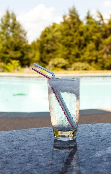 Vaso de agua con cubitos de hielo a un lado de la piscina —  Fotos de Stock