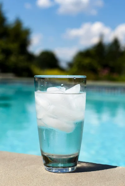 Verre d'eau avec glaçons sur le côté de la piscine — Photo