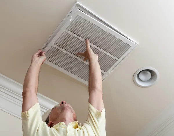 Starszy człowiek otwierając filtr klimatyzacji w sufit — Zdjęcie stockowe