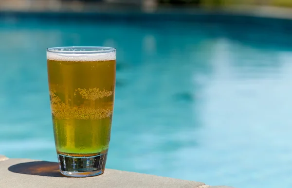 Bicchiere di birra sul bordo a bordo piscina — Foto Stock