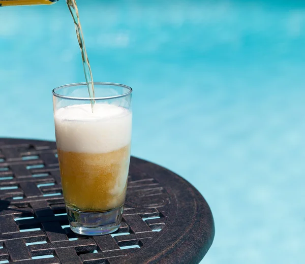 Vaso de cerveza en la mesa junto a la piscina — Foto de Stock