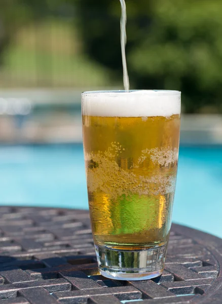 Bicchiere di birra sul tavolo a bordo piscina — Foto Stock