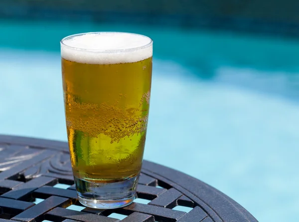 Ποτήρι μπίρα στο τραπέζι από δίπλα στην πισίνα — Φωτογραφία Αρχείου
