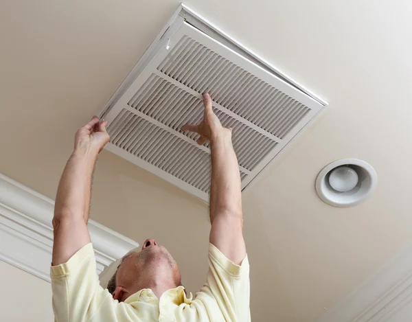 Senior homme ouverture filtre de climatisation au plafond Images De Stock Libres De Droits